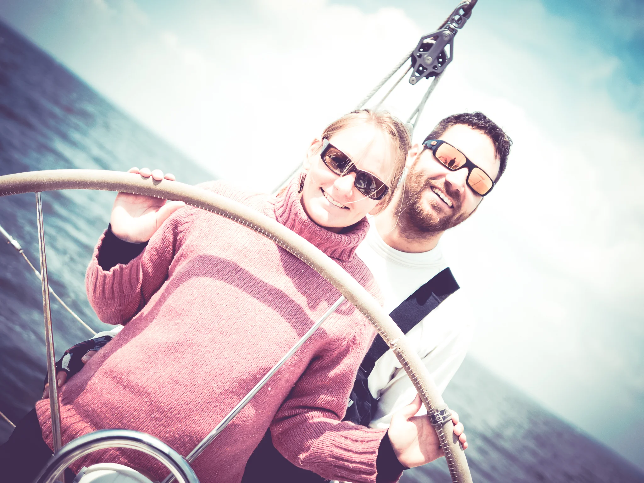 A happy sailor couple behind a sailing boat steering wheel